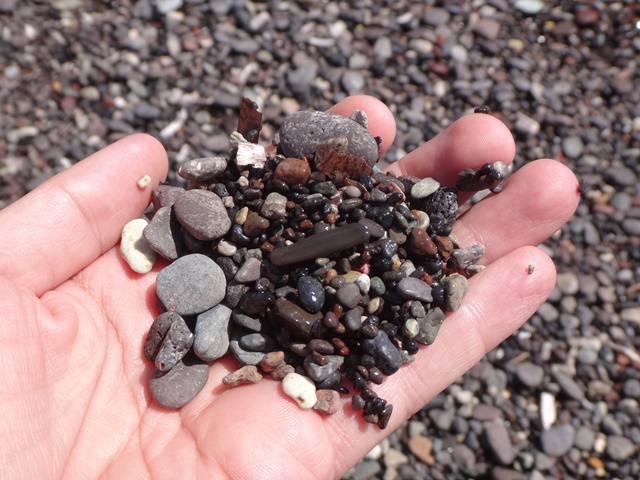 A praia de Perissa é formada por uma areia preta, grossa, repleta de pedras.